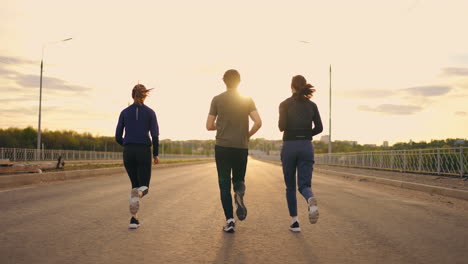 morning-jog-in-outskirts-three-persons-are-running-together-rear-view-of-two-women-and-man